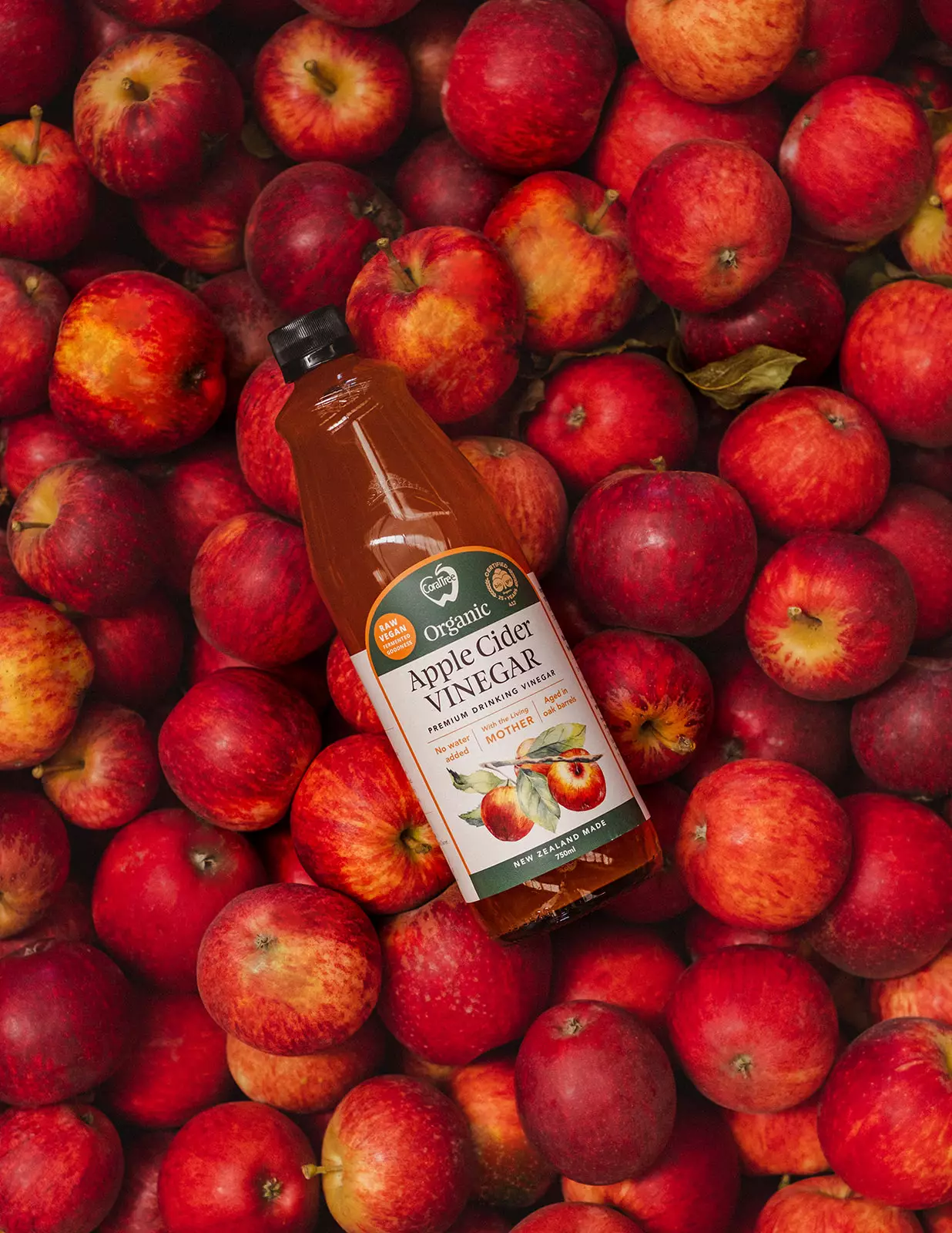 Photo of a 750ml Bottle of Vinegar sits on top of fresh bright red apples.